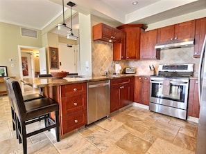 A kitchen with a central island, stainless steel appliances, and wooden cabinets.