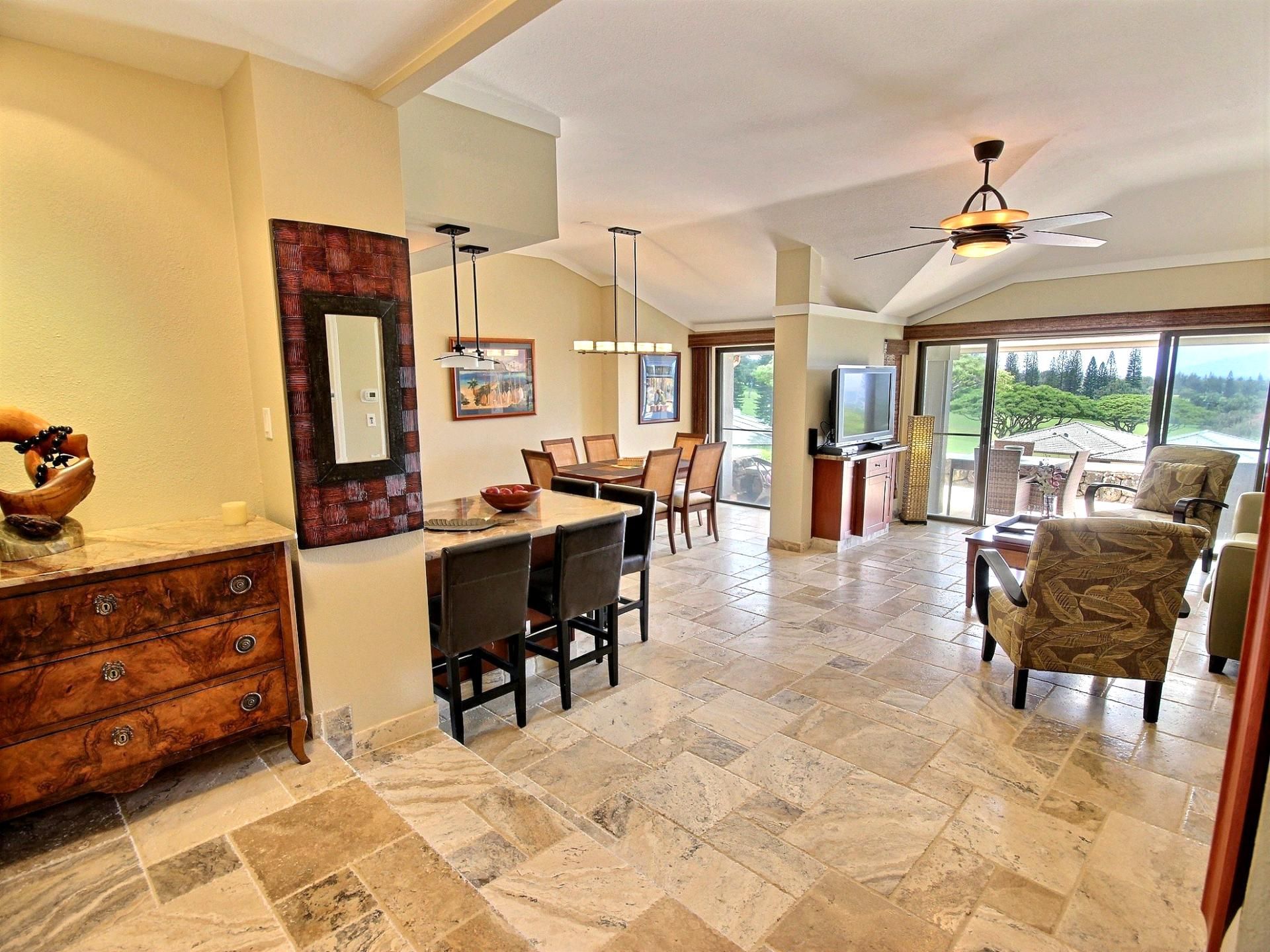 A spacious living area with a dining table, chairs, a fireplace, and a large window offering a view of the outdoors.