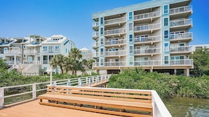 A waterfront residential building with multiple balconies, a wooden deck, and a clear view of the water. - Water View 207 - INTERCOASTAL VIEW Condo! (Indian Shores)