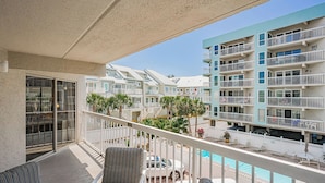 A balcony with a view of a multi-story building, outdoor seating, and a pool. - Water View 207 - INTERCOASTAL VIEW Condo! (Indian Shores)