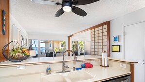 Cozinha moderna com pia dupla, torneira de aço inoxidável e ventilador de teto.