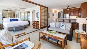 Uma sala ampla com uma cama grande, um sofá, uma mesa de centro e uma cozinha.
