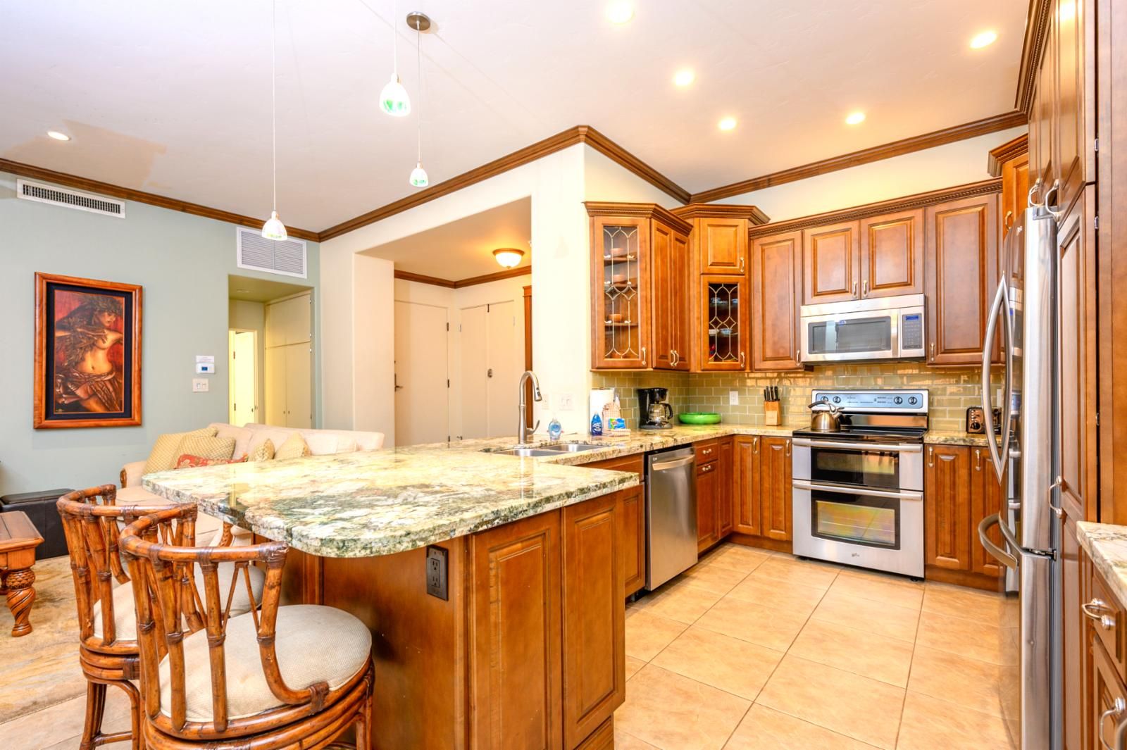 A spacious kitchen with wooden cabinets, a granite countertop, stainless steel appliances, and a dining area with wicker chairs.