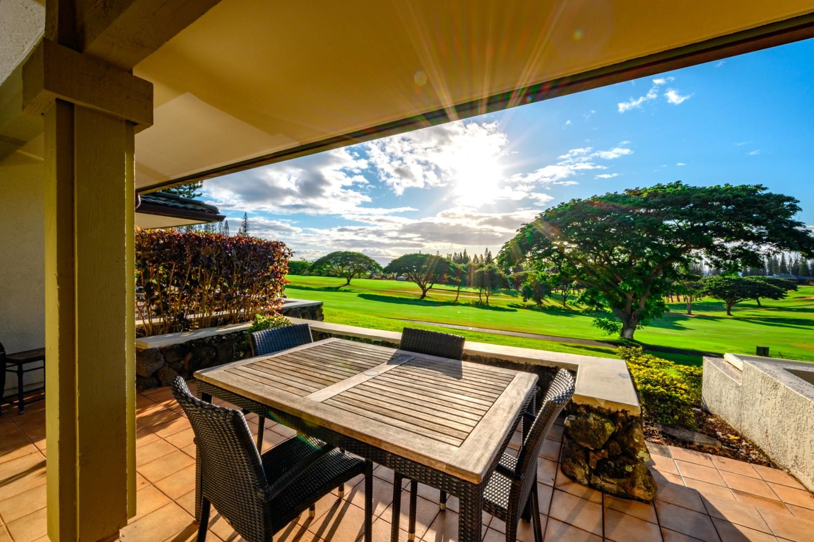 Eine Terrasse mit Tisch und Stühlen mit Blick auf einen Golfplatz.