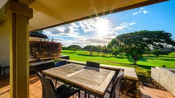 Eine Terrasse mit Tisch und Stühlen mit Blick auf einen Golfplatz.