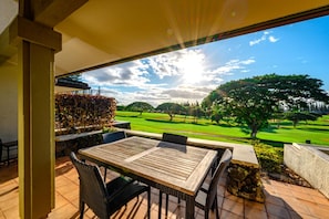 Eine Terrasse mit Tisch und Stühlen mit Blick auf einen Golfplatz.