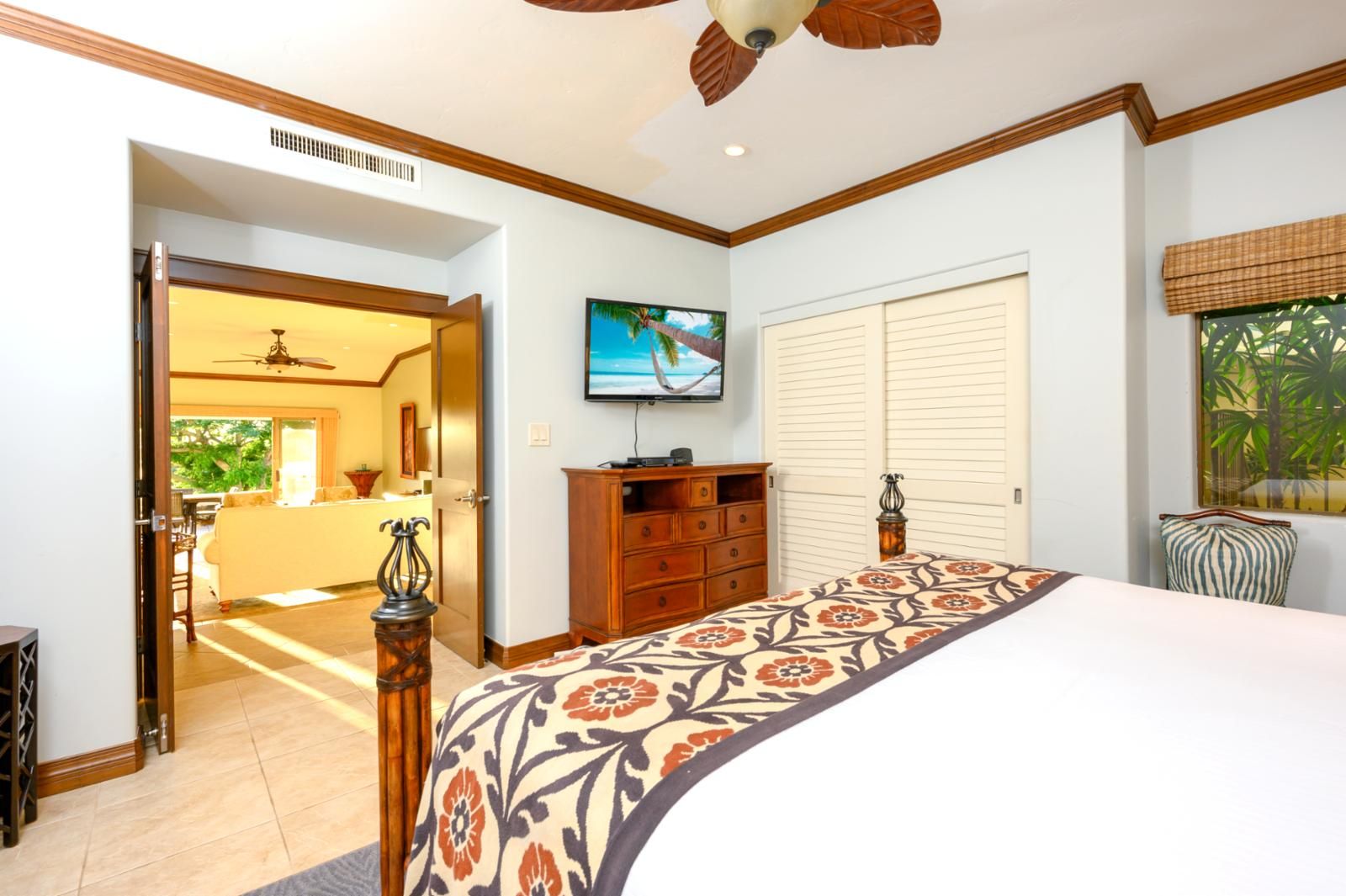 A hotel room with a bed, a TV, a wardrobe, and a view of the outside.