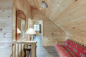 Een houten interieur met een bank, een tafel met een lamp en een vloerkleed met een patroon.
