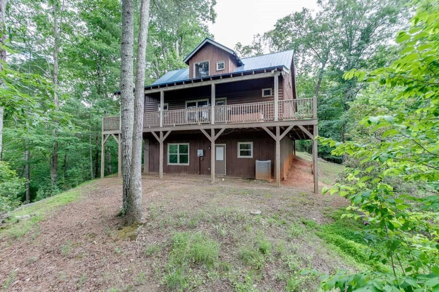 Eine zweistöckige Holzhütte mit Balkon, umgeben von dichtem Wald.