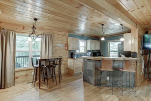 Cozy cabin-style room with a dining area, kitchen, and large window offering a view of the outdoors.