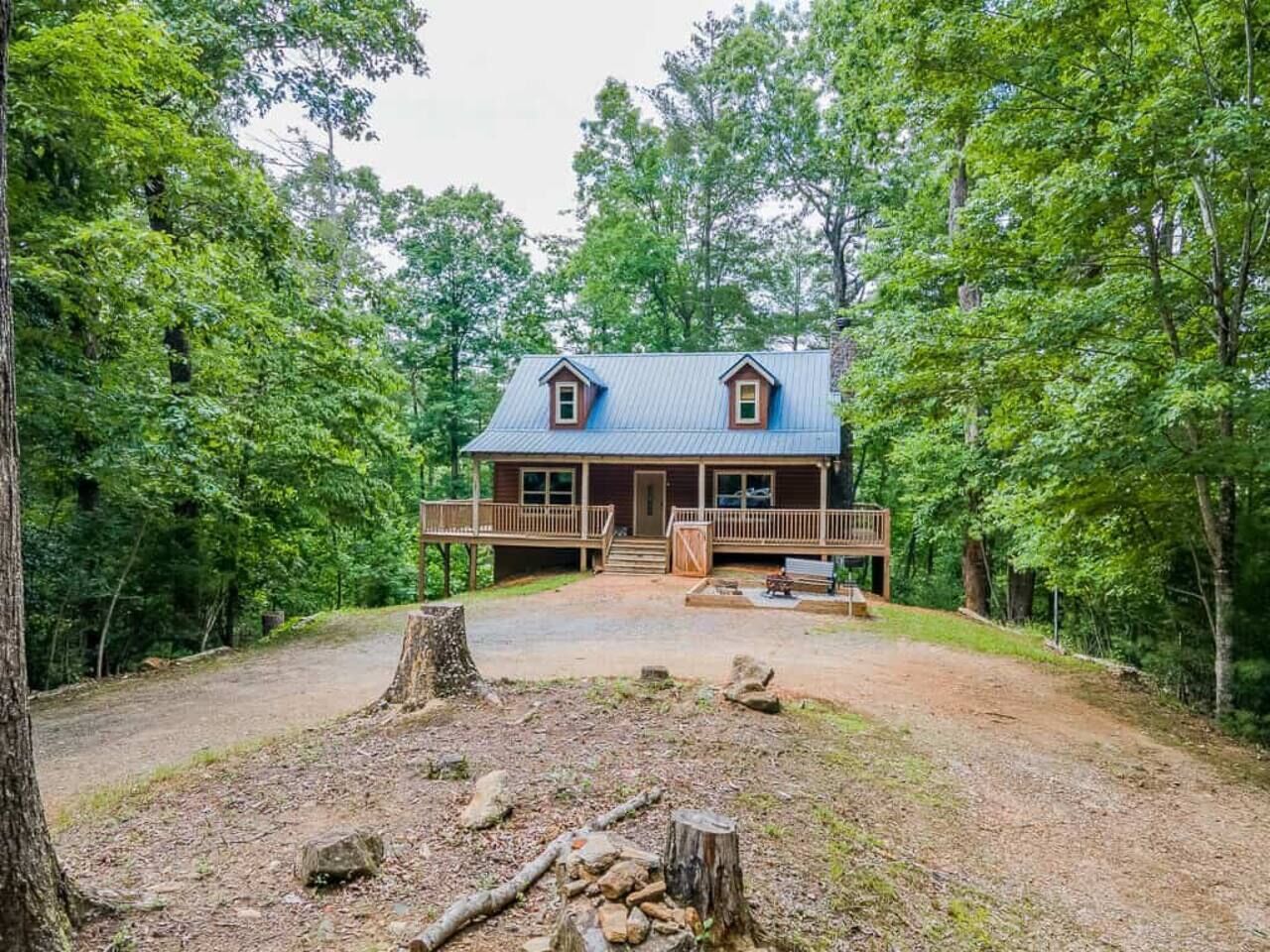 A cabin with a porch, surrounded by trees.