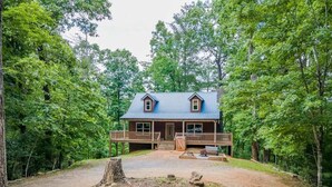 A cabin with a porch, surrounded by trees.