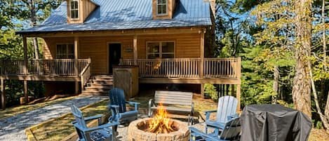 A cabin with a deck, a fire pit, and outdoor seating.