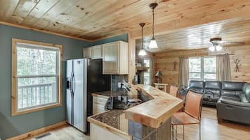 A cabin interior with a kitchen, dining area, and seating space.