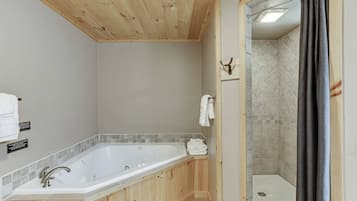 A wooden-paneled bathroom with a large bathtub, a shower area, and a towel rack.
