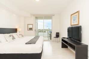 A hotel room with a bed, a TV, a chair, and a balcony with a view. - Spacious condo on high floor with amazing bay & city views. WIFI + Parking (Sunny Isles Beach)