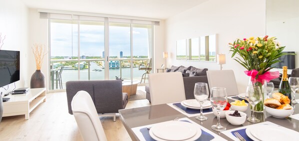 A modern hotel room with a dining area, large windows with a view of the city, and a balcony. - Spacious condo on high floor with amazing bay & city views. WIFI + Parking (Sunny Isles Beach)