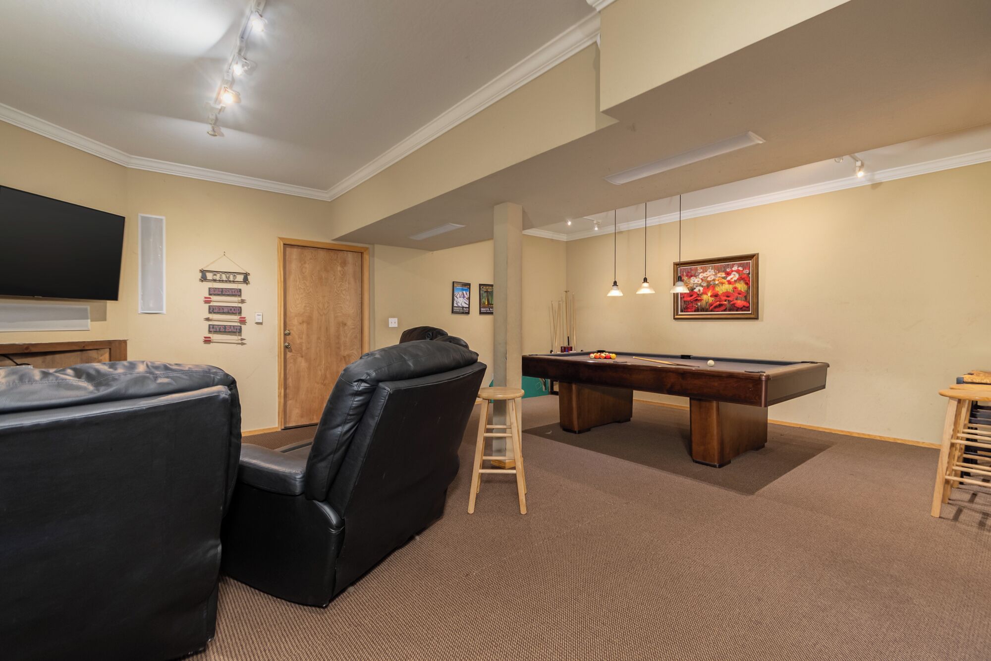 Een kamer met een pooltafel, een televisie en een zithoek met een bank en stoelen.
