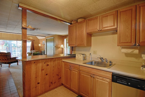 Una cocina con armarios de madera, lavavajillas y pileta.