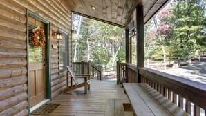 Une cabane en bois avec une véranda, un banc et une porte ornée d’une guirlande.
