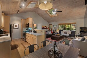 A spacious living area with a dining table set for two, a kitchen with modern appliances, and a cozy seating area with a fireplace.