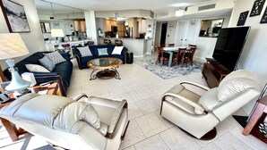 Un salon spacieux comprenant un canapé, deux fauteuils inclinables, une table basse et un téléviseur.
