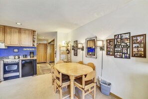 A compact kitchen with wooden cabinets, a stove, and a dining area with a wooden table and chairs.
