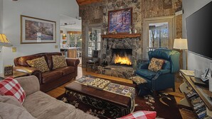 A cozy living room with a stone fireplace, leather sofas, and a television. - Cabin w/ Views, Jacuzzi Bathtub, Fireplace, Screened Porch, Outdoor Hot Tub (Ferguson)