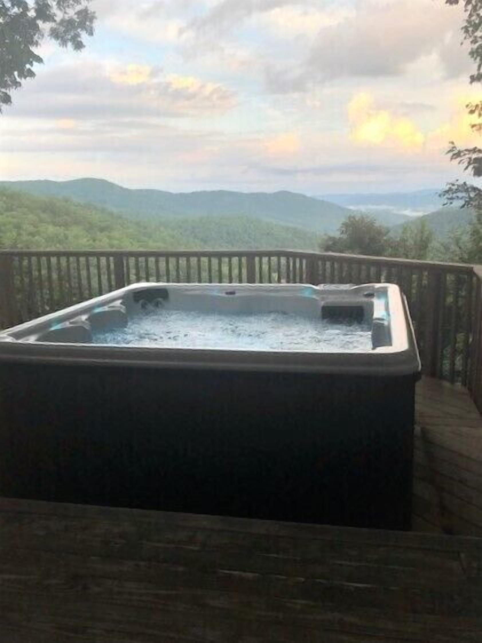 A hot tub on a wooden deck with a view of mountains.
