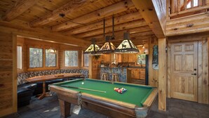 Ein Holzblockbau-Innenraum mit Billardtisch, Bar und Steinwand.