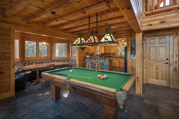 A wooden cabin interior with a pool table, a bar area, and a stone wall. - Mountain Cabin,Hot Tub,Pool/Ping Pong Table,Pet-Friendly (Ferguson)