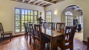 A dining area with a large wooden table surrounded by chairs, large windows, and a wooden ceiling. - Villa Tranquila ~ Historic Mediterranean Home, Mountain Views, Spa! (Guerneville)