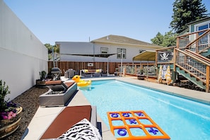 Un jardin avec une piscine, du mobilier d’extérieur et une terrasse en bois.