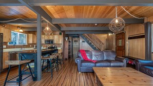 Eine geräumige Küche mit Holzausstattung, ein Essbereich mit Ledersofa und eine Treppe, die zu einer weiteren Ebene führt.
