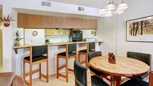 A compact kitchen with wooden cabinets and a central island. There is a dining area with a round wooden table and four chairs. - 2 bedrooms, 6 blocks from Main Street, Frisco! Bike path right outside! (Frisco)