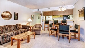 A living room with a patterned sofa, a wooden coffee table, and a dining area with wooden chairs and a table. - 2 bedrooms, 6 blocks from Main Street, Frisco! Bike path right outside! (Frisco)