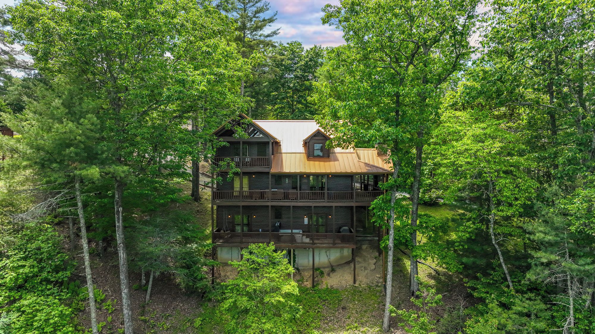 A multi-story cabin surrounded by dense forest.