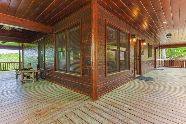 A wooden cabin with large windows, a porch, and a view of the outdoors.