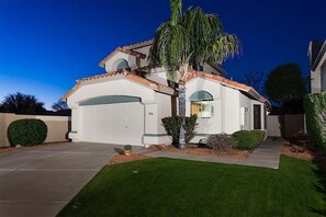A two-story house with a white exterior, a garage, and a well-maintained lawn. - Gilbert Island Cozy 2 BR Home/ Putting Green/ COM Pool/ Gilbert (Gilbert)
