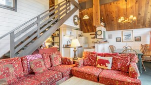 A cozy living room with a wooden staircase, a dining area, and a kitchen. - Chalet #6, Charming Cabin Perfect Location steps t (Mammoth Lakes)