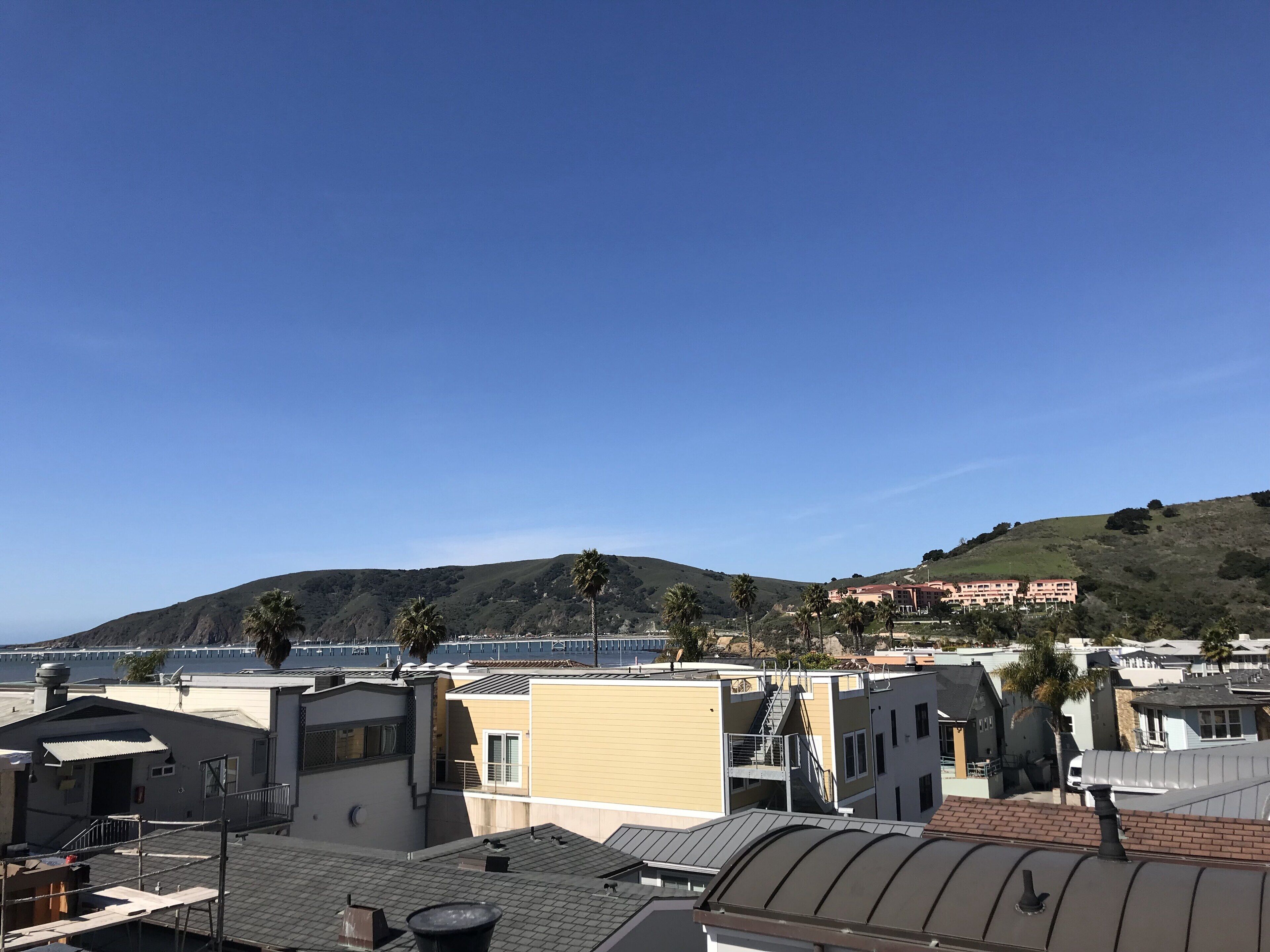 Ett bostadsområde med moderna byggnader, en sluttning och en klarblå himmel.