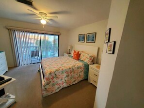 A bedroom with a bed, a nightstand, a dresser, a ceiling fan, and a window with blinds.