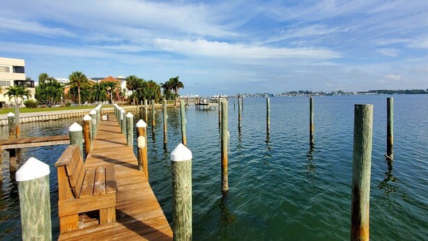 A wooden pier extending into calm water, with a clear sky above.