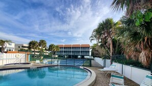 A swimming pool with a 4 FT depth marker, surrounded by lounge chairs and palm trees.