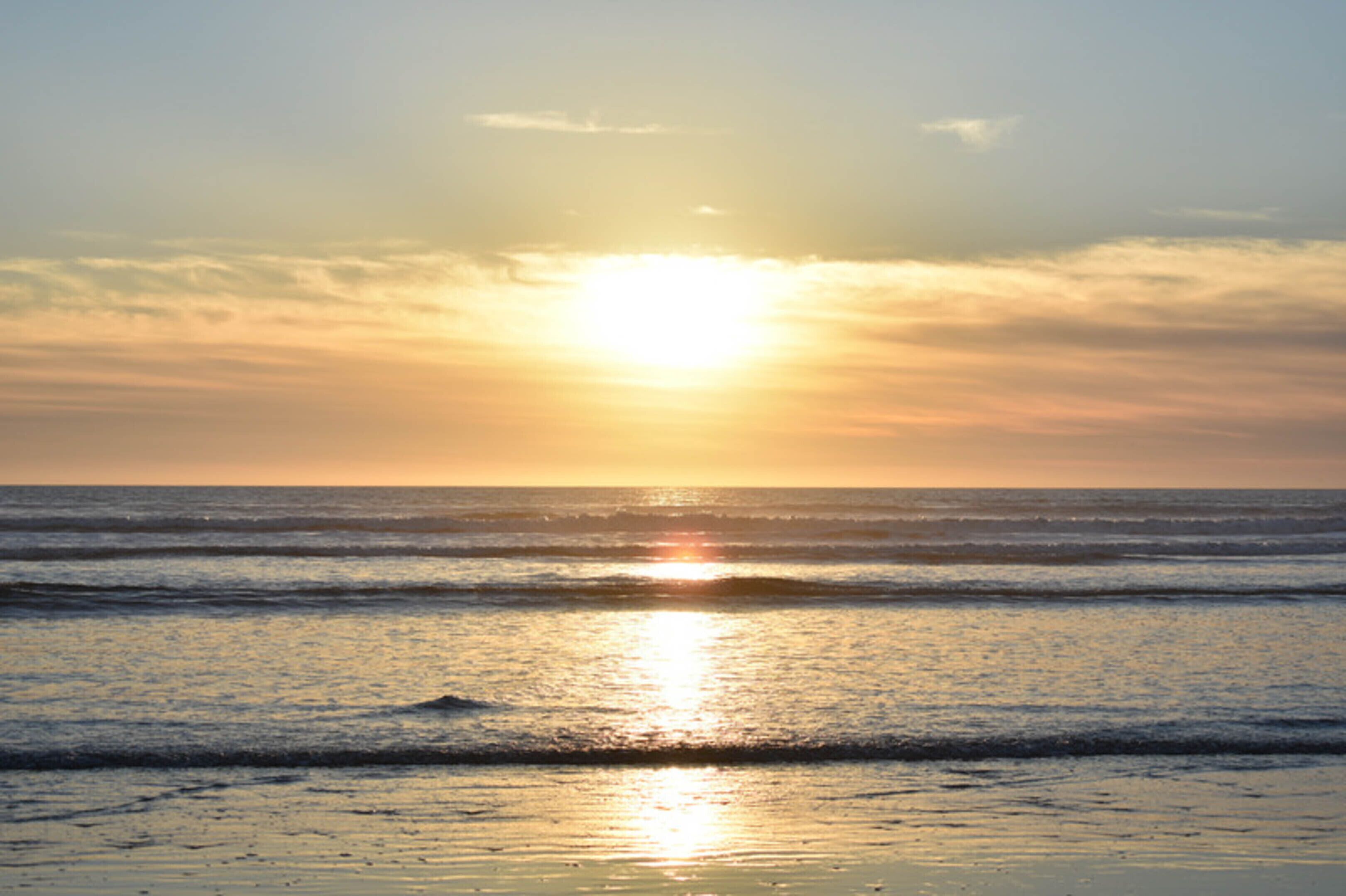 A sunset over the ocean with calm waves.
