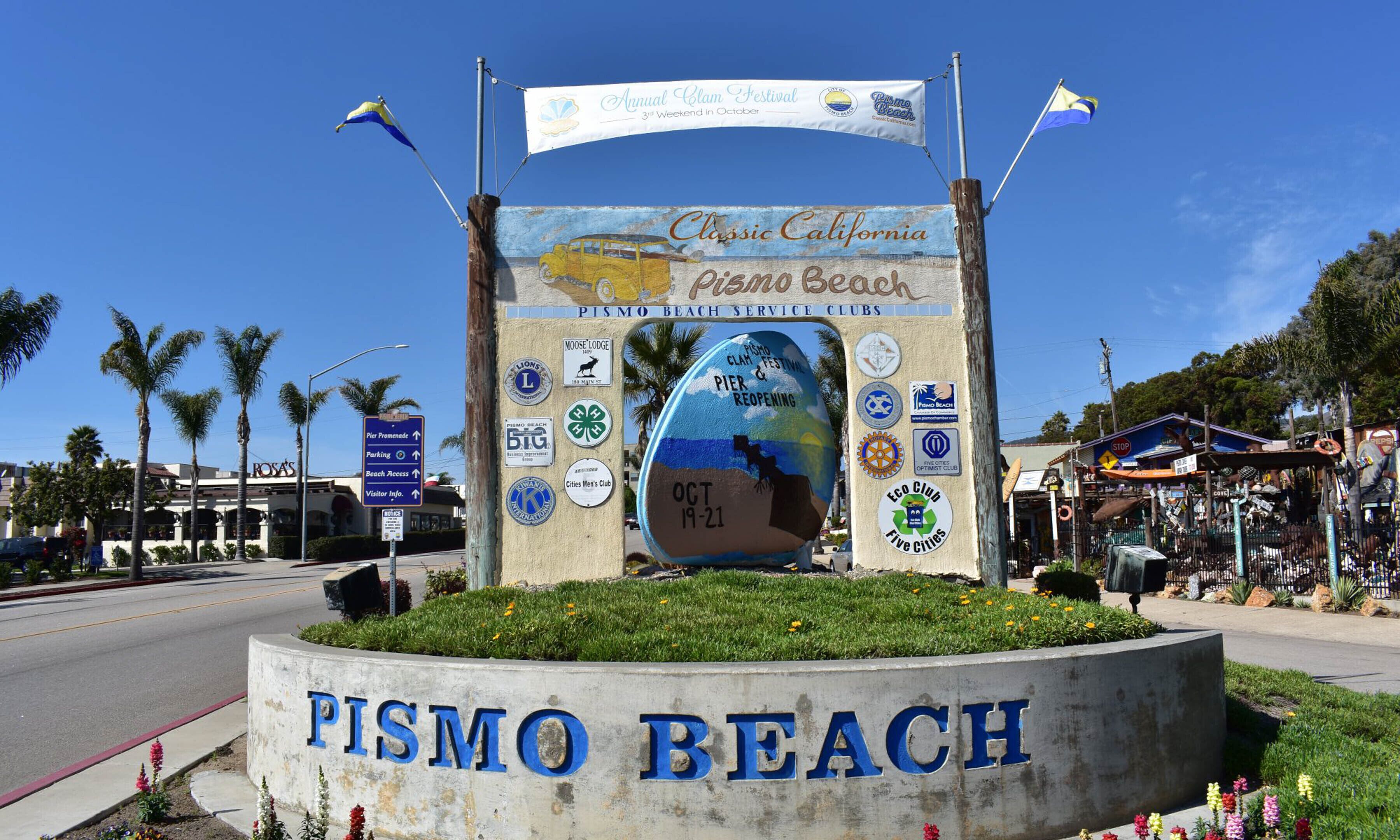 A sign for Pismo Beach with multiple logos and a globe indicating a festival.
