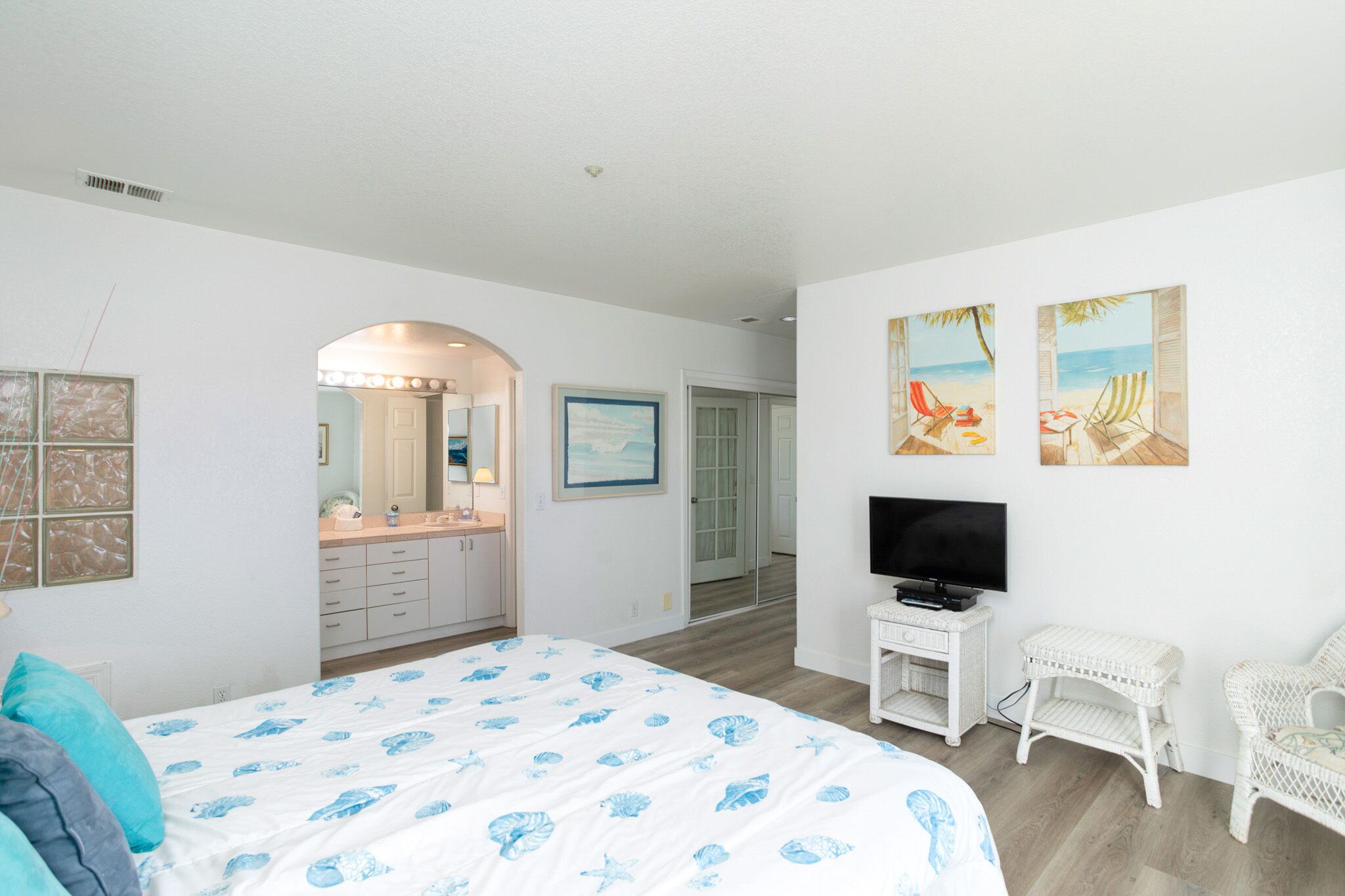 Ein Schlafzimmer mit einem großen Bett, einem Fernseher und Kunstwerken an der Wand.