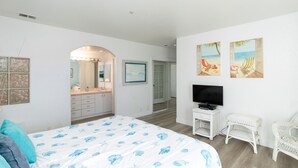 Ein Schlafzimmer mit einem großen Bett, einem Fernseher und Kunstwerken an der Wand.