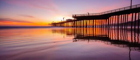 A pier extending into calm waters at sunset with a clear sky.