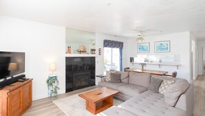 Ein Wohnzimmer mit Fernseher, Sofa, Couchtisch, Kamin und einem Essbereich mit Tisch und Stühlen.